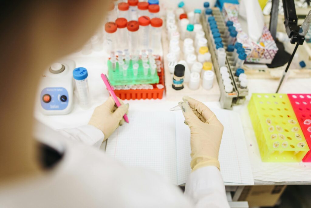 Scientist analyzing samples in a lab with various test tubes and equipment.