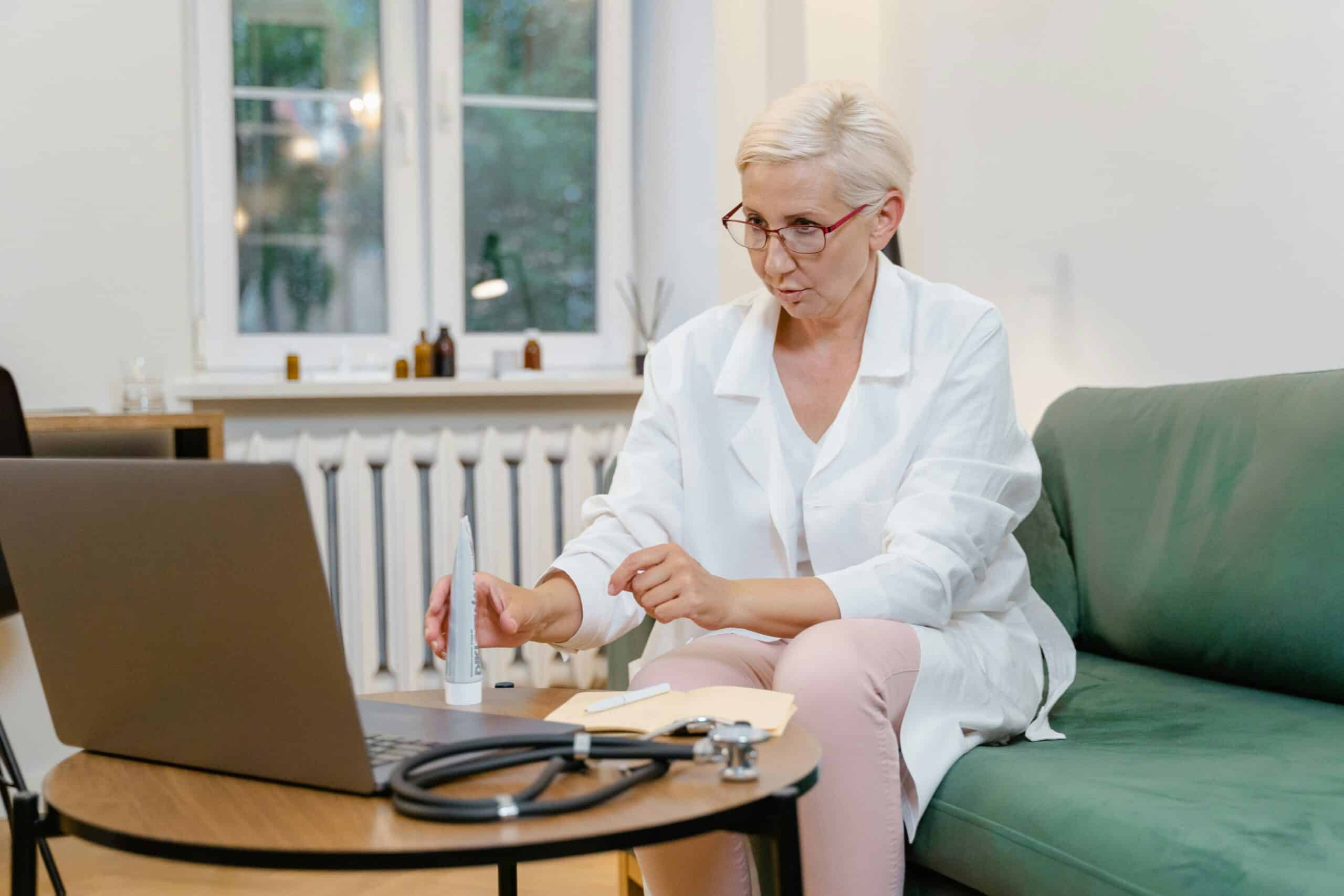 Elderly female doctor conducting an online consultation from her home office.