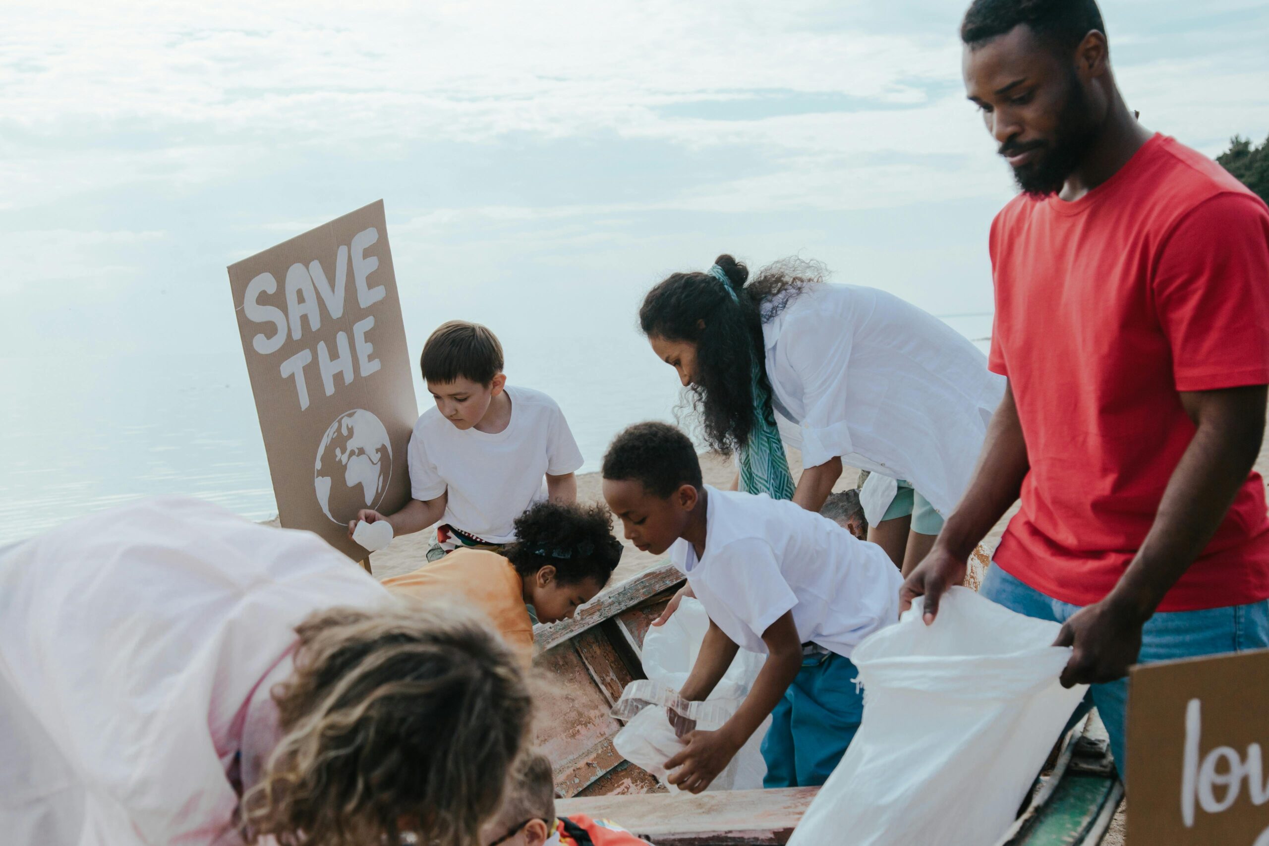 Diverse group of volunteers cleaning up a beach, promoting environmental protection and teamwork.